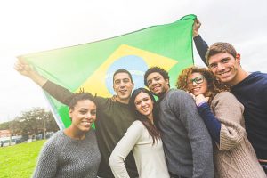 A group of friends holding the flag of Brazil.