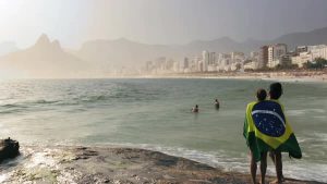 Two expats standing on the beach wrapped in the Brazilian flag.
