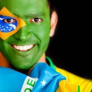 Smiling young man whose face is painted like the Brazilian flag