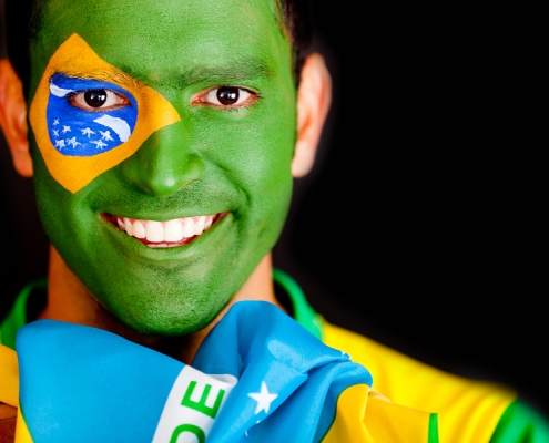 Smiling young man whose face is painted like the Brazilian flag