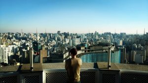 Young man observing the city's landscape after moving to Sao Paulo.