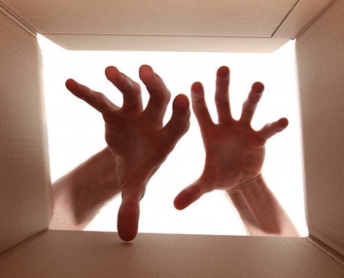 Two open hands reaching inside a box