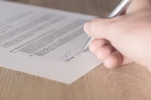 A hand holding a pen, signing an international moving insurance contract 