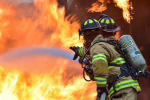 Dois bombeiros extinguindo um incêndio enorme