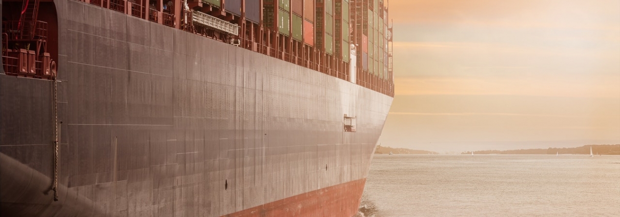 A large ship carrying cargo, cloudy sky and gray water