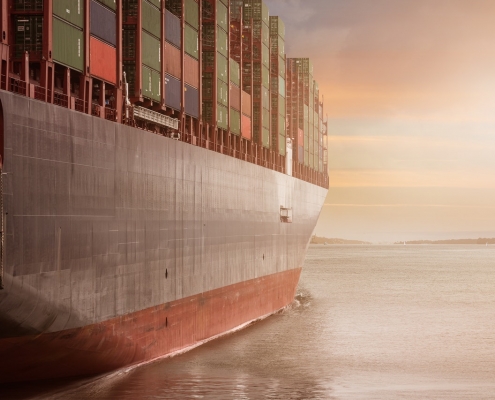 A large ship carrying cargo, cloudy sky and gray water